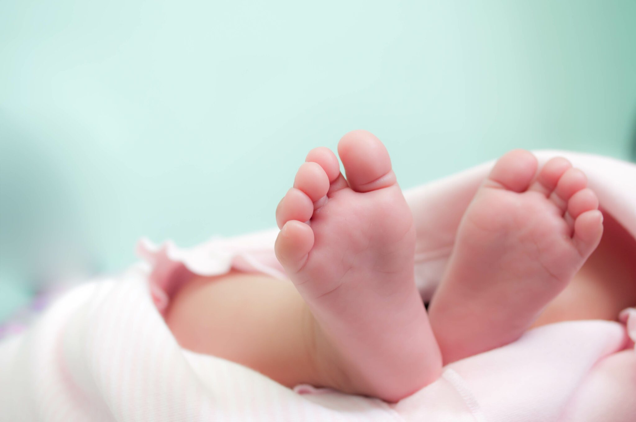 Stock photo showing the soles of a baby's feet laying on a white blanket